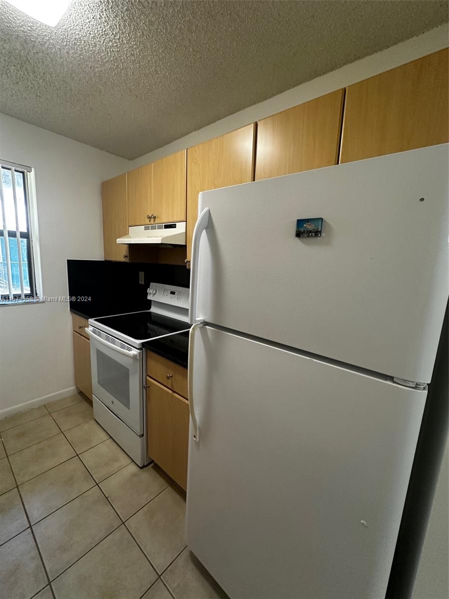 a white refrigerator freezer and a stove sitting inside of a kitchen