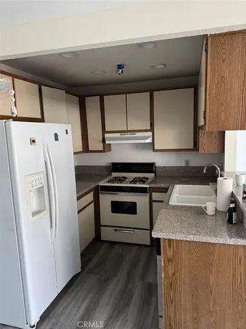 a kitchen with granite countertop a refrigerator stove and sink