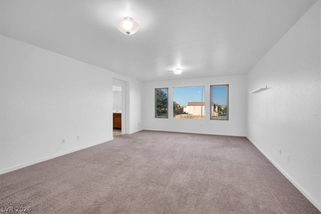 8046 Noble Ridge Street Las Vegas, NV 89139 - Photo 15 of 34 A spacious, naturally illuminated room features plush carpeting and multiple windows offering suburban views.