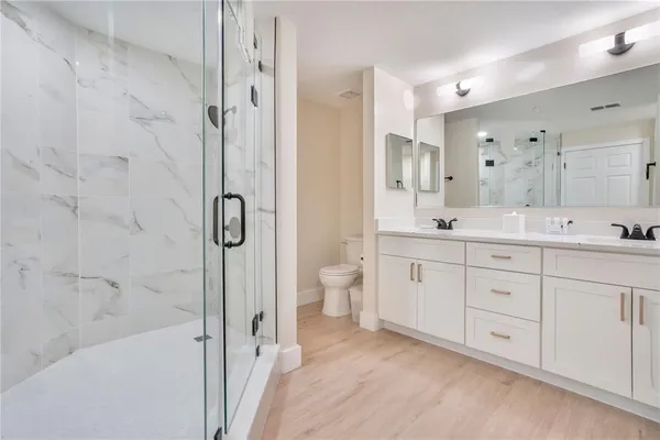 a spacious bathroom with a granite countertop sink a toilet mirror and shower