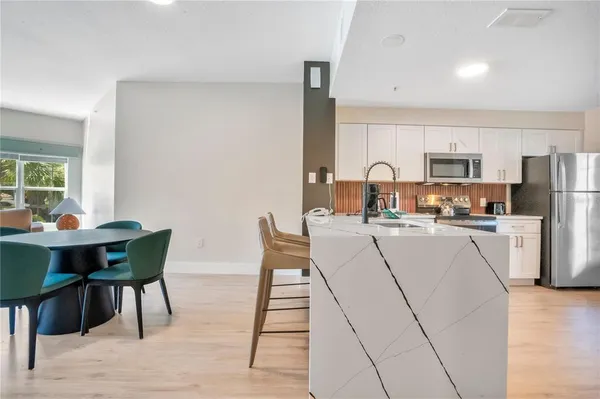 a living room with furniture a table and kitchen view