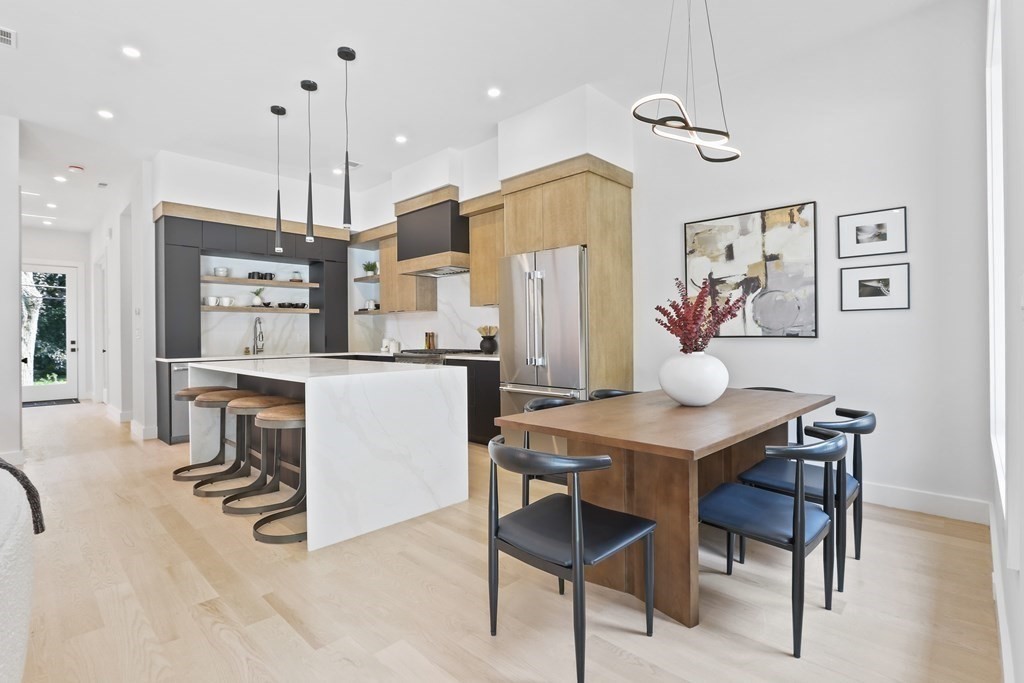 70 Washington Street, Unit 70 Newton, MA 02458 - Photo 5 of 25 a kitchen with stainless steel appliances kitchen island granite countertop a table chairs and a refrigerator