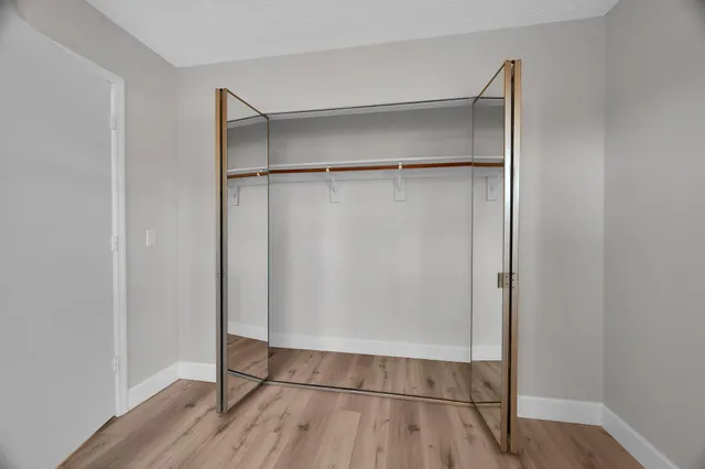 a view of an empty walk in closet with wooden floor