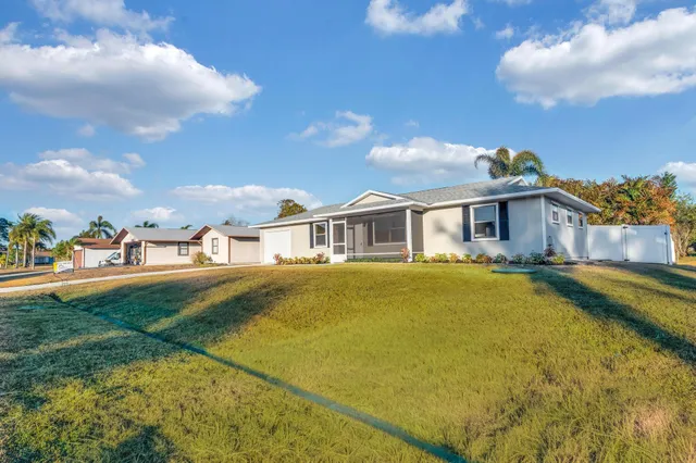 a view of a large pool with lawn chairs under an umbrella