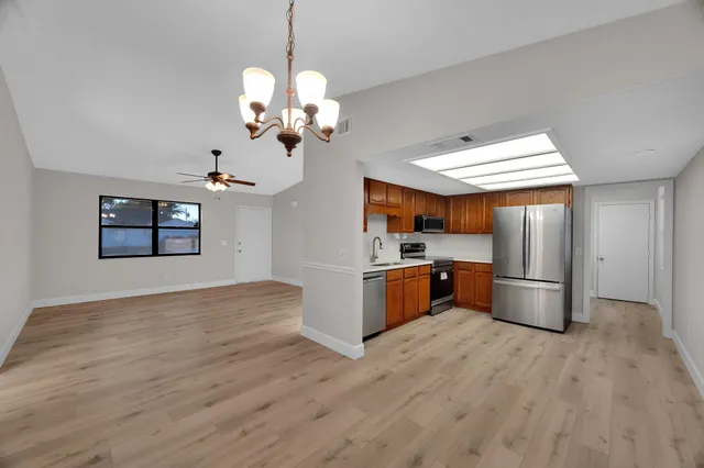 a kitchen with stainless steel appliances granite countertop a refrigerator a sink dishwasher a stove with wooden floor