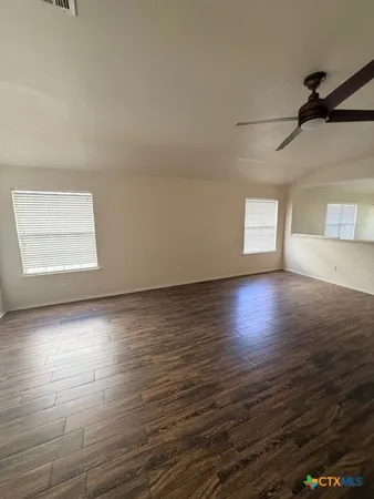 an empty room with wooden floor and windows