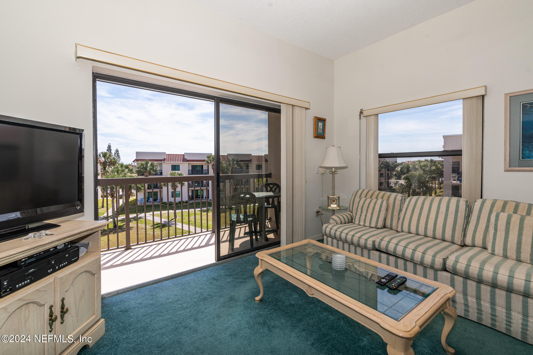 4250 A1A South, Unit Q31 (ELEVATOR) St. Augustine, FL 32080 - Photo 13 of 45 a living room with furniture a flat screen tv and a floor to ceiling window