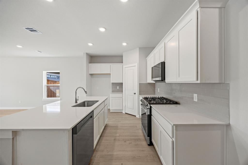 734 Carson Drive Forney, TX 75126 - Photo 5 of 31 a kitchen with stainless steel appliances granite countertop a sink a stove and a refrigerator