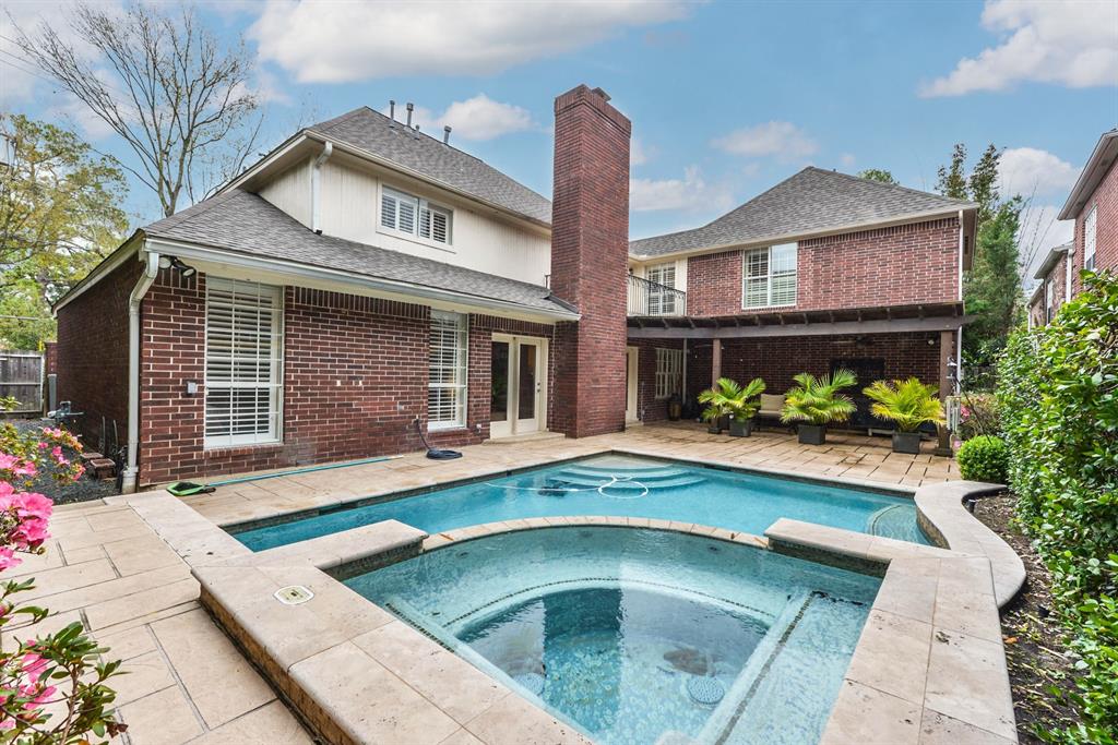 Gorgeous private backyard with sparkling waterfall pool and spa, covered outdoor living with stamped overlay flooring.