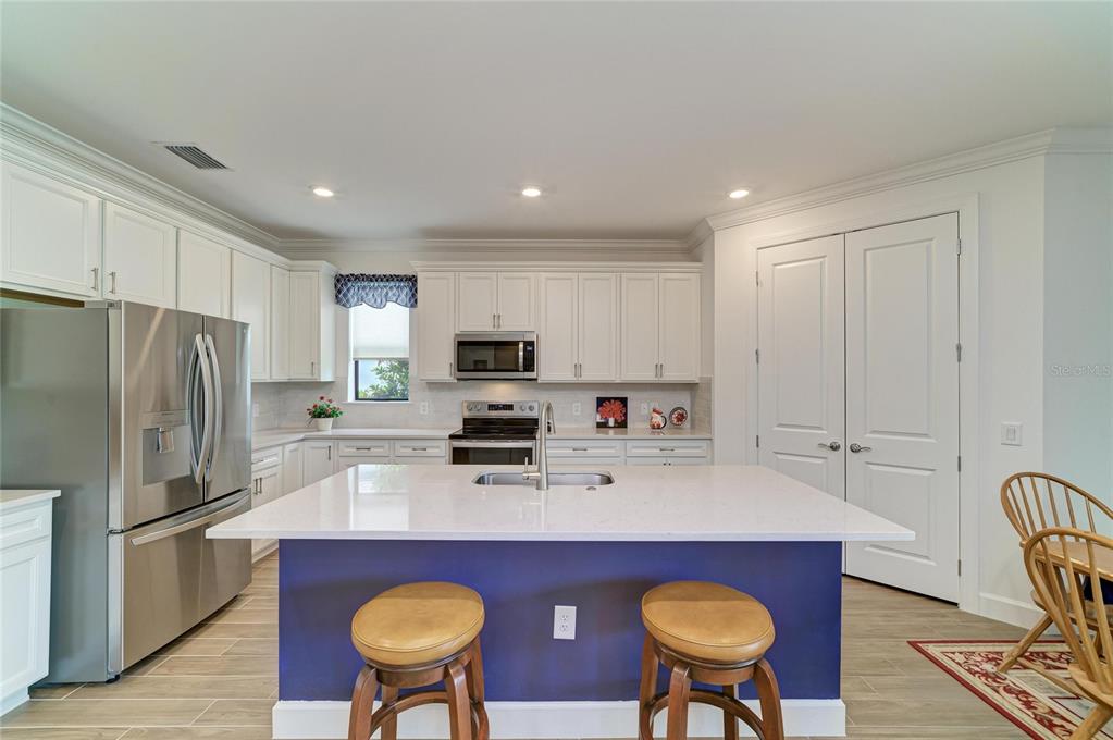 16341 Hidden Oak Loop Lakewood Ranch, FL 34211 - Photo 18 of 76 a kitchen with stainless steel appliances a sink a stove a refrigerator cabinets and dining table
