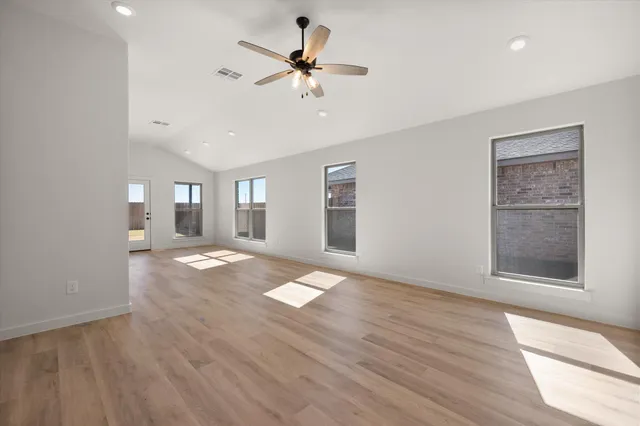 a view of an empty room with a window and wooden floor
