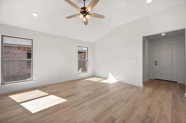 a view of an empty room with a window and wooden floor