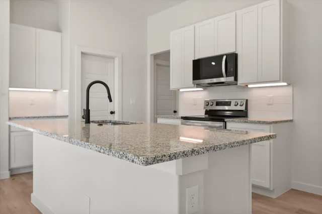 a kitchen with stainless steel appliances granite countertop a sink a stove a microwave a sink and dishwasher with wooden floor