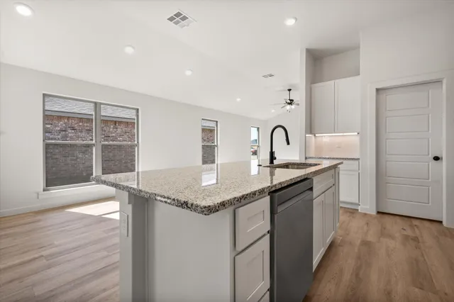 a kitchen with granite countertop a sink cabinets and wooden floor