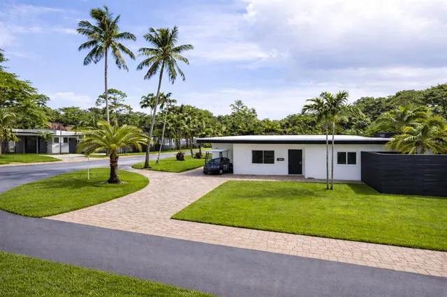 a palm tree sitting in front of a house with a yard