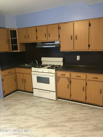 a kitchen with stainless steel appliances granite countertop a stove a sink and white cabinets