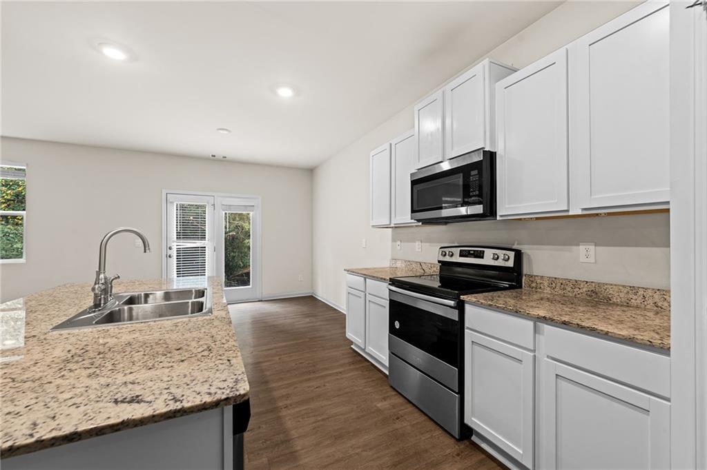 297 Starbuck Parkway Pendergrass, GA 30567 - Photo 21 of 50 a kitchen with granite countertop a stove sink and microwave