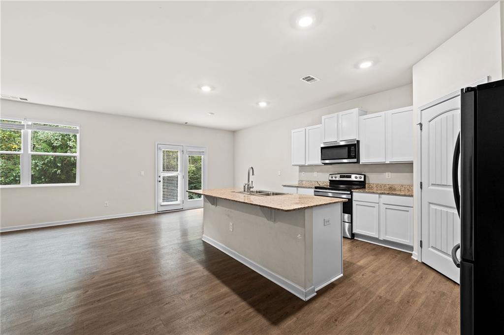 297 Starbuck Parkway Pendergrass, GA 30567 - Photo 5 of 50 a kitchen with stainless steel appliances a sink a stove a refrigerator cabinets and a window