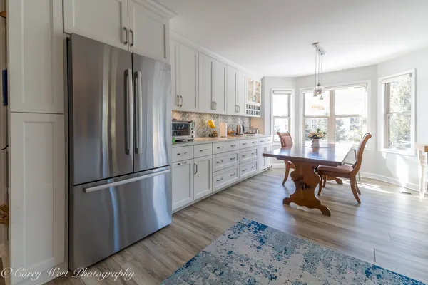 a kitchen with stainless steel appliances granite countertop a refrigerator a stove a sink dishwasher a dining table and chairs with wooden floor