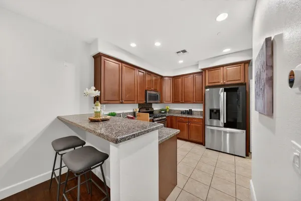 a kitchen with stainless steel appliances granite countertop a refrigerator and a stove top oven