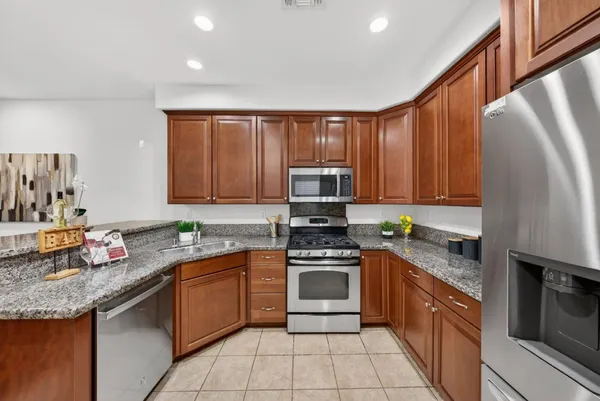 a kitchen with stainless steel appliances granite countertop wooden cabinets a stove top oven a sink and dishwasher