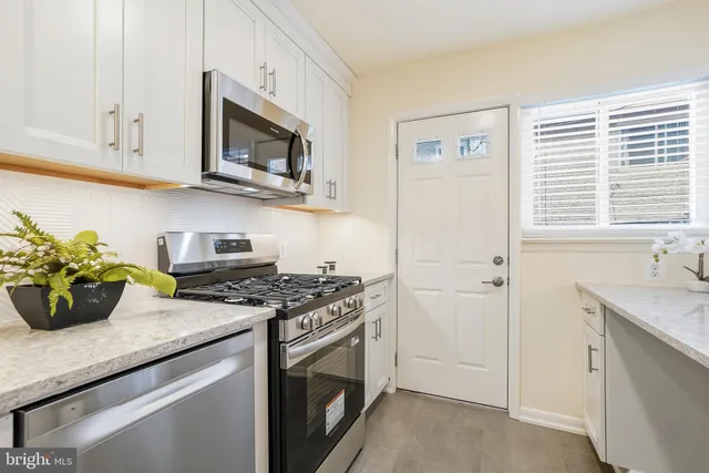 a kitchen with stainless steel appliances granite countertop white cabinets and a stove