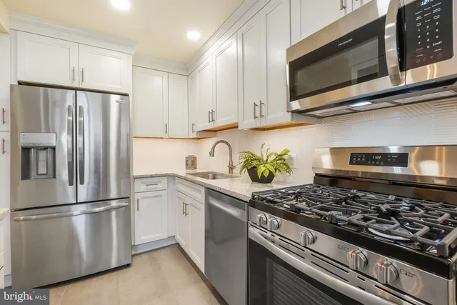 a kitchen with stainless steel appliances granite countertop a refrigerator stove top oven and sink