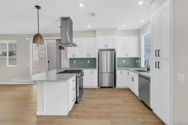 a kitchen with stainless steel appliances granite countertop a refrigerator a stove and a sink