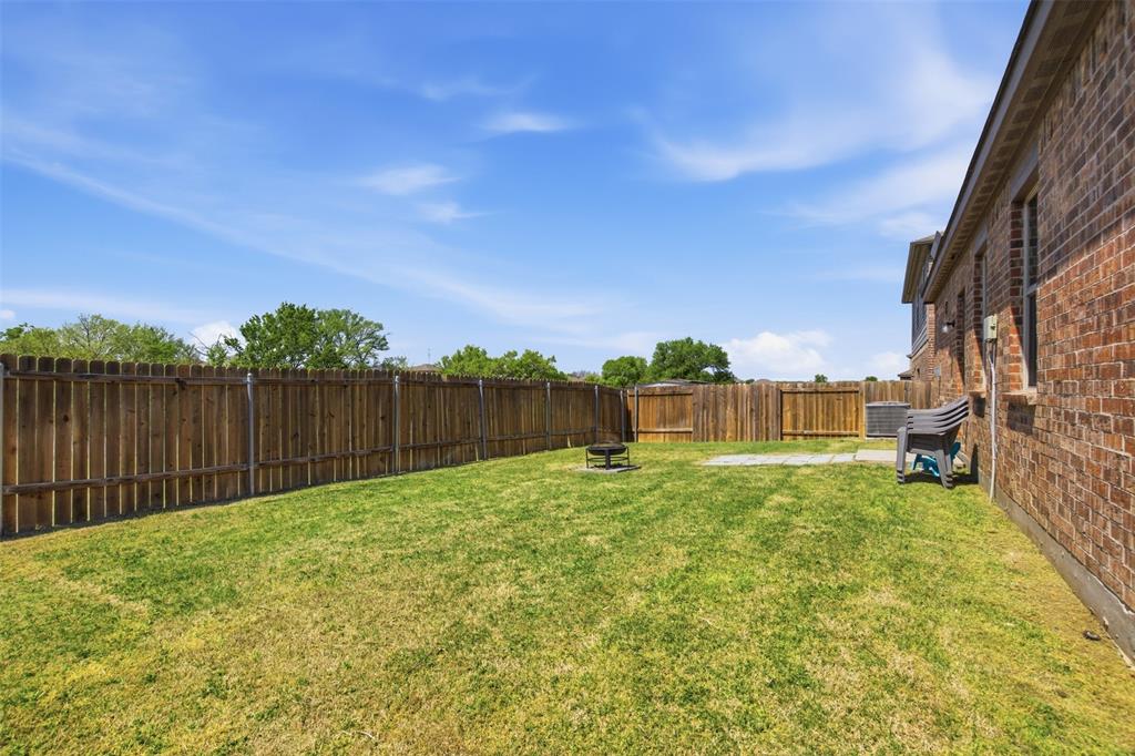 292 Wandering Stream Way Princeton, TX 75407 - Photo 37 of 40 Expansive grassy backyard featuring a full privacy fence, brick exterior, and a concrete patio pad
