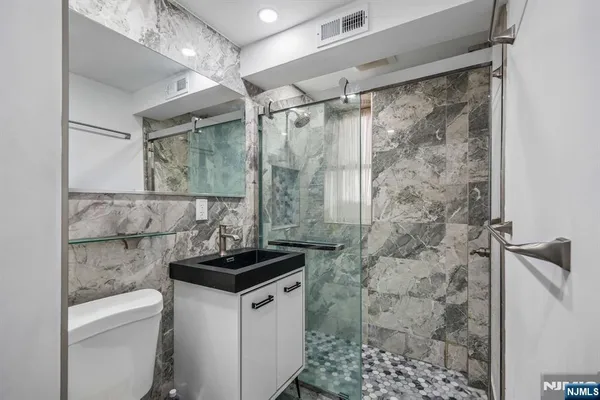 a bathroom with a granite countertop shower a toilet and a shower