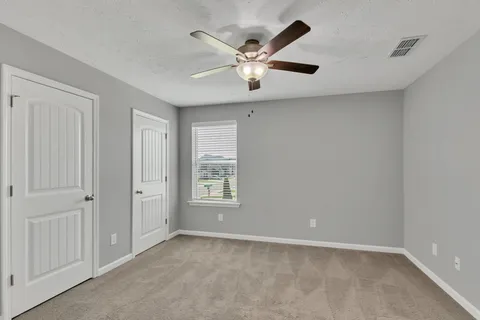 an empty room with windows and fan