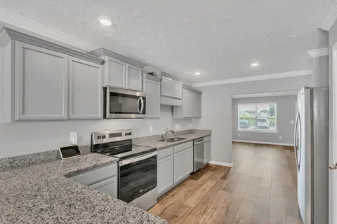 a kitchen with stainless steel appliances granite countertop a stove a sink and a microwave