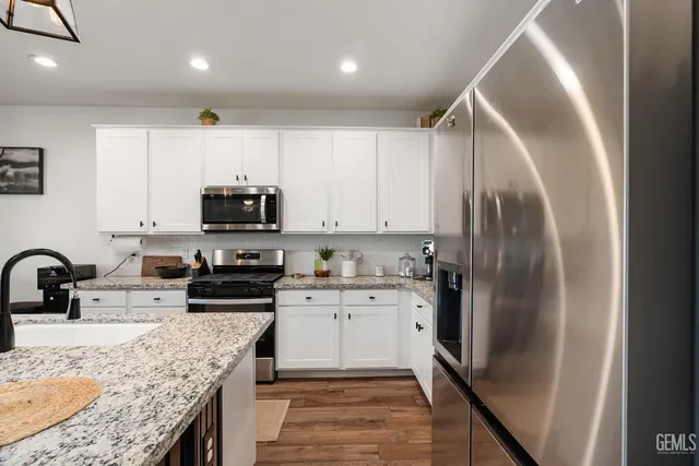 a kitchen with stainless steel appliances granite countertop a refrigerator a stove top oven a sink and dishwasher