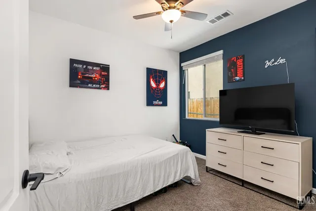 a bedroom with a bed and a flat tv screen on dresser