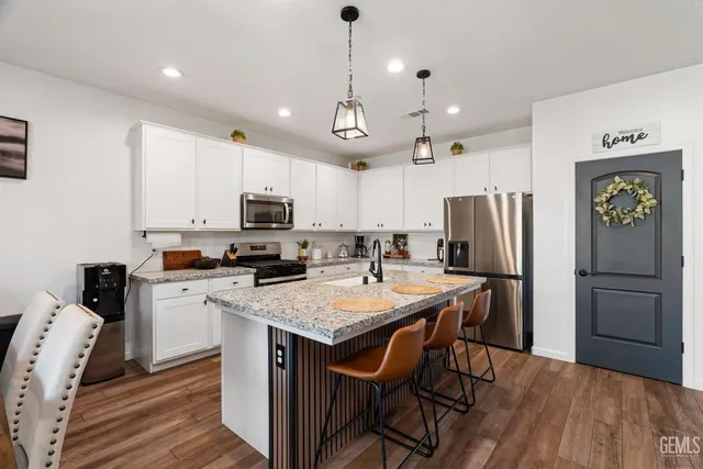 a kitchen with a refrigerator a stove a microwave oven a sink a dining table and chairs