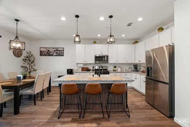 a kitchen with a dining table chairs refrigerator and microwave