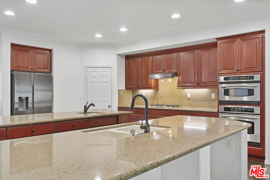 23871 Rio Ranch Way Valencia, CA 91354 - Photo 11 of 46 a kitchen with kitchen island granite countertop a sink and counter space