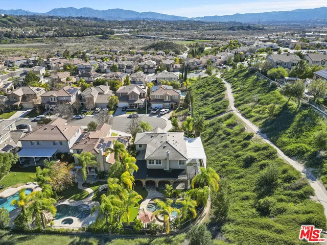 an aerial view of residential houses with outdoor space and trees