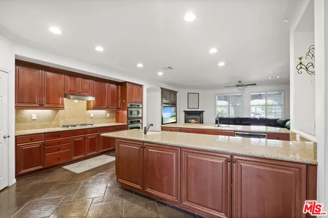 a large kitchen with stainless steel appliances wooden cabinets and a counter top space