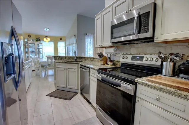 a kitchen with stainless steel appliances granite countertop a stove a sink a microwave a dining table and chairs