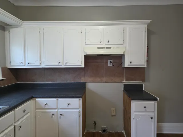 a kitchen with white cabinets and sink