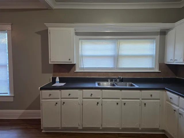 a kitchen with granite countertop white cabinets and a window