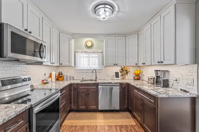 a kitchen with stainless steel appliances granite countertop a sink stove oven a sink dishwasher and cabinets with wooden floor