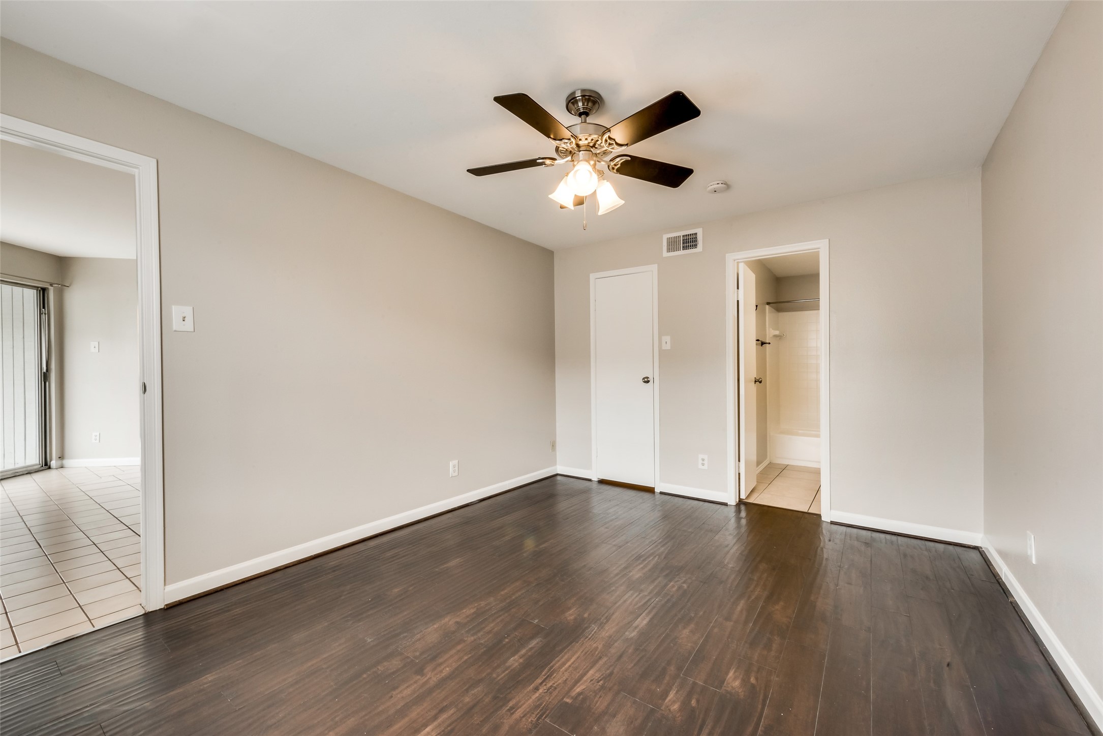8787 Brae Acres Road, Unit 406 Houston, TX 77074 - Photo 8 of 15 a view of an empty room with wooden floor and a ceiling fan