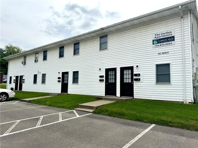 a view of a white house with a yard next to a road