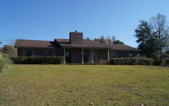 a front view of house with yard and trees in the background