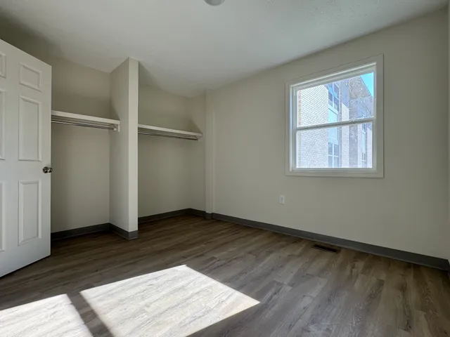 an empty room with wooden floor cabinet and windows