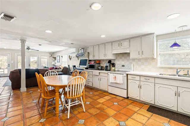 a kitchen with stainless steel appliances granite countertop a sink a stove a dining table and chairs