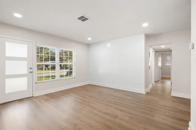 an empty room with wooden floor and windows