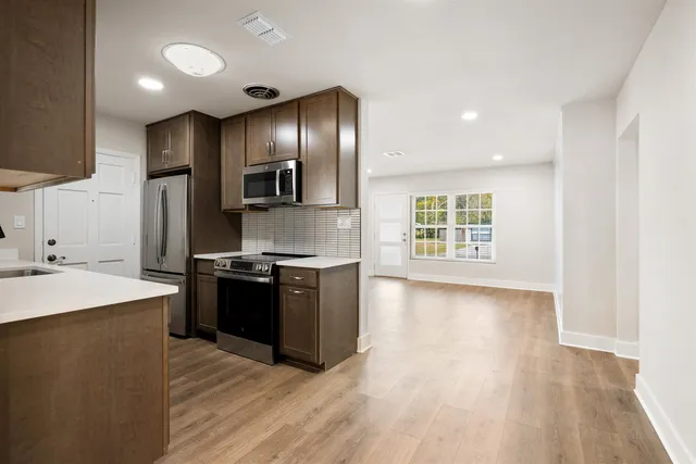 a large kitchen with stainless steel appliances granite countertop a stove a sink and a refrigerator